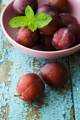 Obraz premium Bowl with plums on blue shabby wooden background