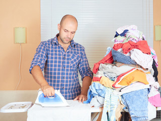Caucasian man ironed clothes in the room near the window.
