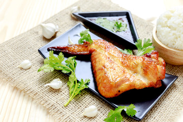 Wing of chicken grilled on the black plate with sweet sauce or c