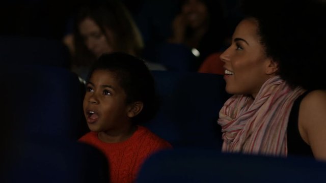  Young family watching a film in crowded movie theatre