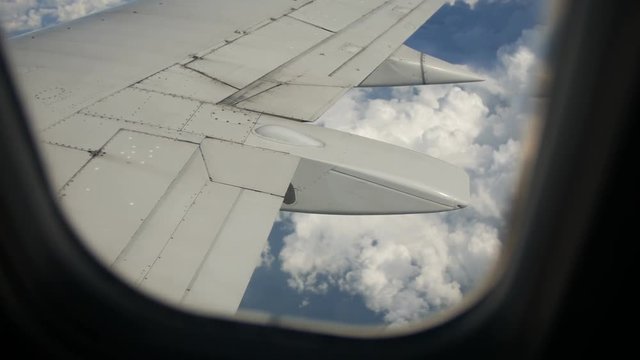 Ground and clouds under wing of an airplane during flight