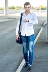 Obraz premium Young stylish man in a hurry looking at his watch