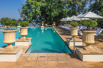 Beautiful Swimming Pool with deck chairs and pottery and Zambezi River in the background
