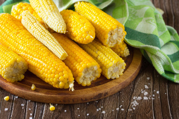 Cooked sweet corn and salt on a wooden table.