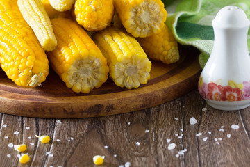 Cooked sweet corn and salt on a wooden table.
