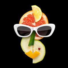 Fruity Picasso / Quirky food concept of Picasso style female face in sunglasses made of fresh fruits on black background.