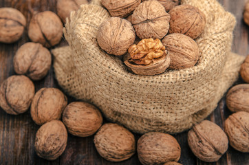 Walnuts on a bag,   wooden background