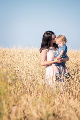 Portrait of mother and her baby boy in a wheat gold field with blue sky