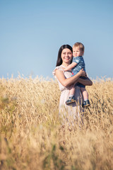 Portrait of mother and her baby boy in a wheat gold field with blue sky