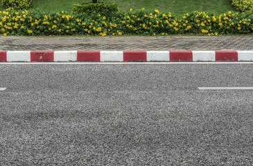 Asphalt road with red and white concrete curb