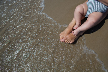 Mother and her infant son wash their legs in the sea
