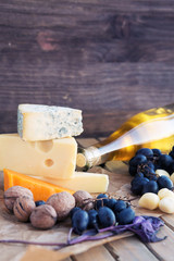 Cheese plate on the wooden board with grape, walnut, wine