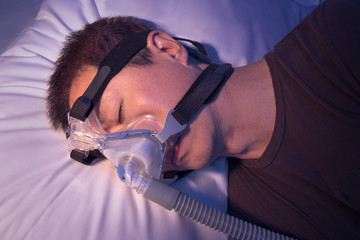 Middle age asian man with sleep apnea sleeping using CPAP machin - obrazy, fototapety, plakaty