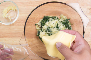 Putting cheese to spinach bowl