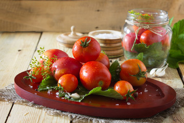 Preserving fresh and pickled tomatoes, spices and garlic on a wo