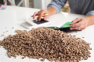 Hands on calculator calculationg household heating costs. Wooden pellets, biomass, effective, environmentally friendly and economical heating, sustainable and renewable energy.
