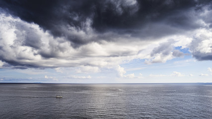 Boot auf hoher See mit Sturmwolken am Himmel
