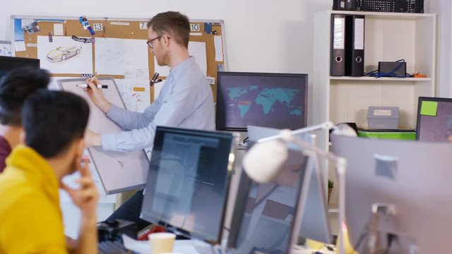  Young creative technical design team working in office with lots of computers