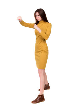 skinny woman funny fights waving his arms and legs. Isolated over white background. Long-haired brunette in a mustard-colored dress in boxing.