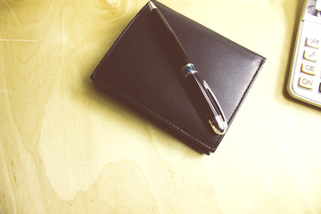 wallet with a calculator and a pen on the desktop