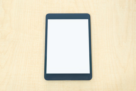 Digital tablet similar to ipade style on wood desk on top view.