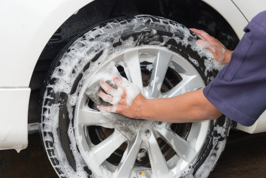 Hand man worker washing car's alloy wheels on a car wash