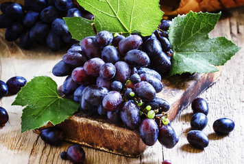 Blue grapes on old wooden table, selective focus