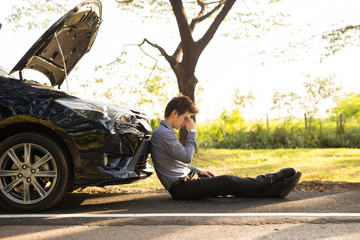 Full length of businessman with hands on head sitting by broken down car at countryside