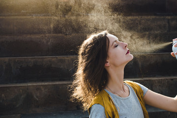 Young woman spraying face with thermal water. Enjoying, skin care concept.