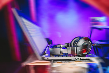 Dj laptop with headphones at nightclub. In the background laser light show and smokes