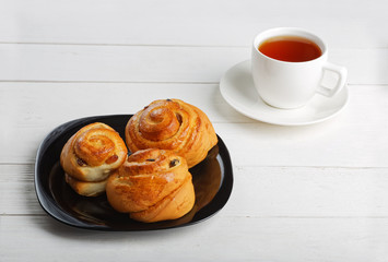 Raisin Buns and cup of tea on white table