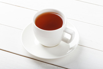 White cup of tea on a white wooden table.