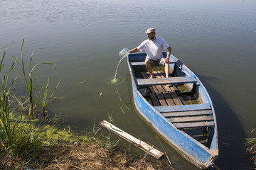 Мужчина выливает воду из старой лодки   © i_valentin
