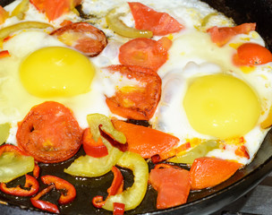 cooking fried eggs with tomatoes,red pepper, paprika in a pan