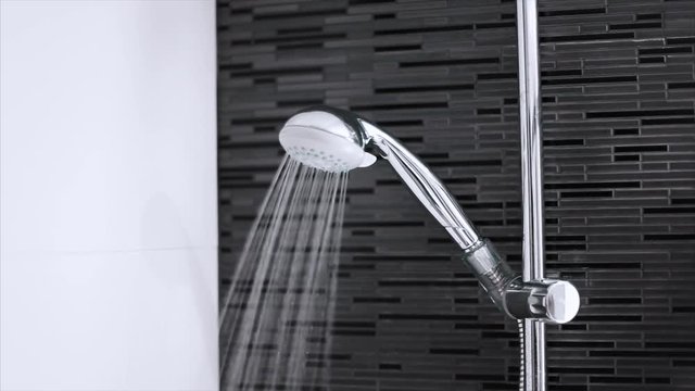 Shower faucet flowing water on a clean bright bathroom