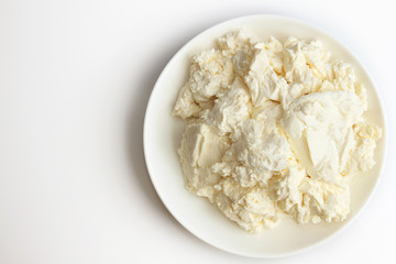Fototapeta na wymiar Cottage cheese in white saucer on white background.