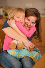 Mother hugs her cute little daughter