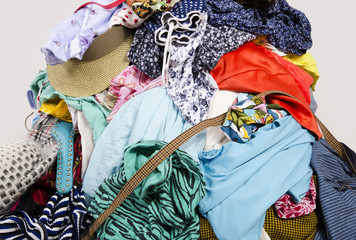 Close up on a big pile of clothes and accessories thrown on the floor. Untidy cluttered wardrobe with colorful clothes and accessories.