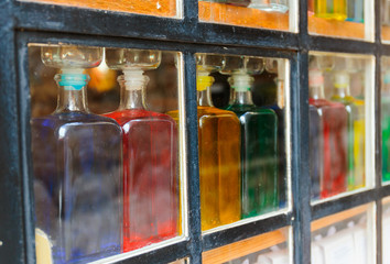 Bottles with colored liquid on the window behind the glass