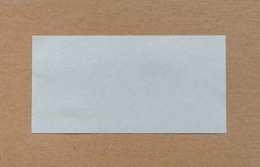 Blank white paper label on brown cardboad background