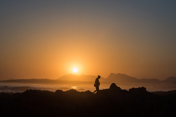 Fototapeta na wymiar Persona osserva il tramonto sul mare