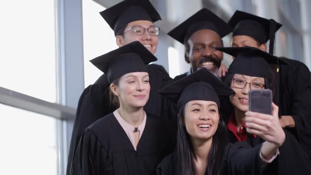  Happy group of mature students on graduation day pose for selfie with phone
