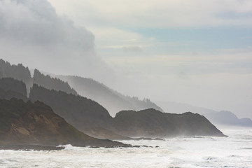 Misty and Foggy Oregon Coast cliffs and forests with stormy sky and ocean waves