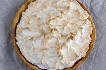 Top view on Meringue cake with strawberry jam on baking paper