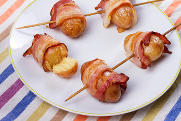 Bacon-wrapped potato in white plate.