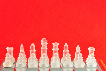 Chess pieces on a chess board isolated against a red background