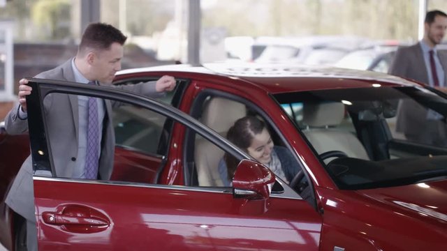  Excited couple in car dealership take key to new car from salesman