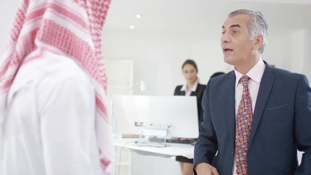  Smiling Arab businessmen meeting & shaking hands in office
