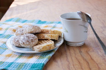 Spoon on a mug and saucer with cakes and rolls