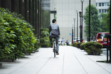 Back figure of businessman riding a road bike